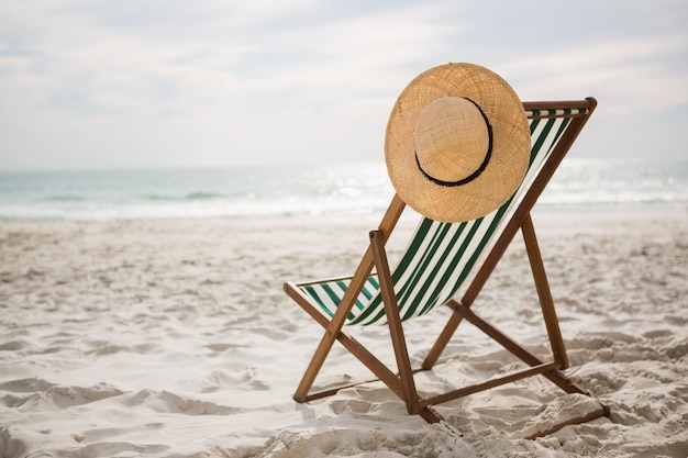 Straw hat kept on empty beach chair