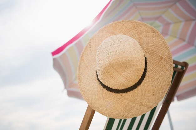 Straw hat kept on empty beach chair