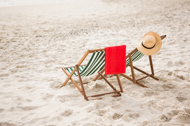 Foto gratuita cappello di paglia e asciugamano conservati su sedie da spiaggia