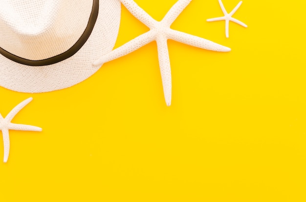 黄色のテーブルの上の海の星と麦わら帽子