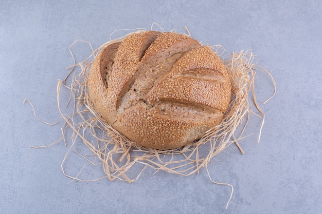 Straw pile under a loaf of bread on marble surface