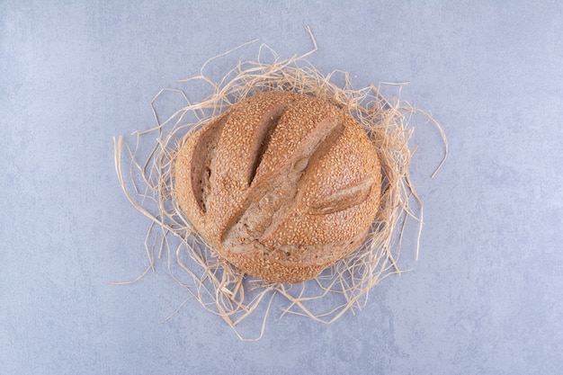 Straw pile under a loaf of bread on marble surface