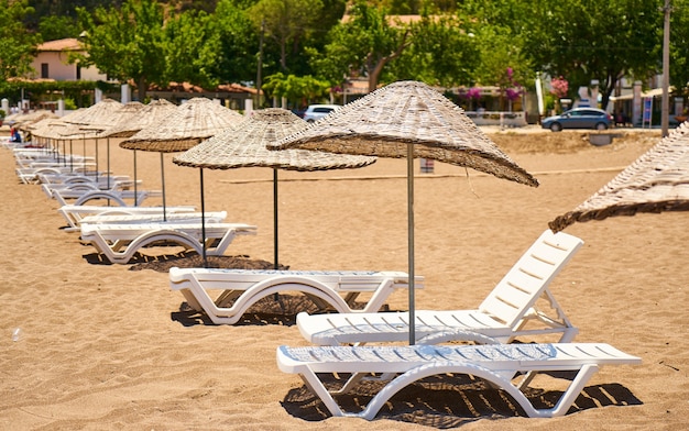 Foto gratuita ombrelloni di paglia con sedie a sdraio su una spiaggia