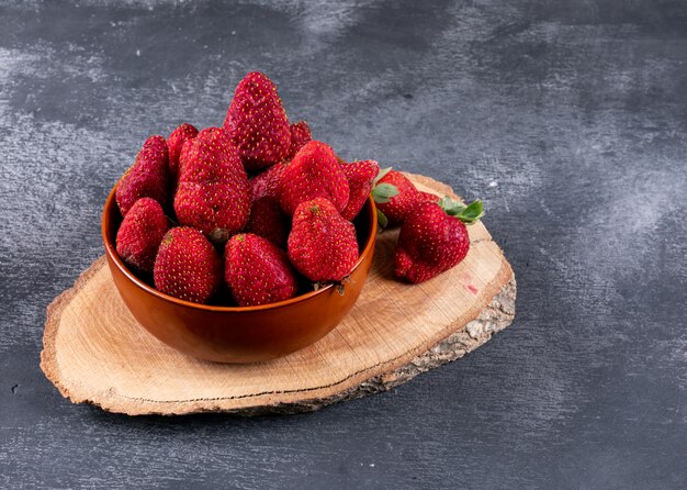 strawberries in bowl on a stub and dark table