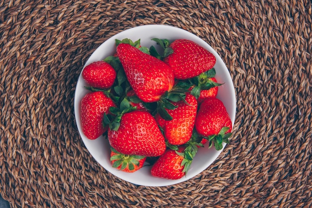 Strawberries in a bowl on a textured background. top view.