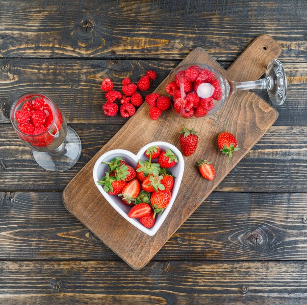 Strawberries in bowl with raspberries in glasses