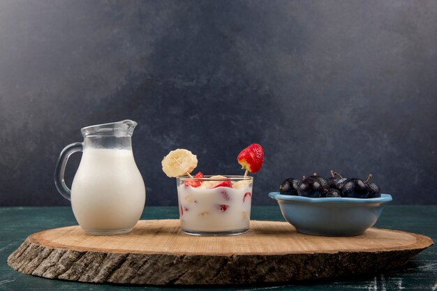 Strawberries in cream served with milk and cherries on black background