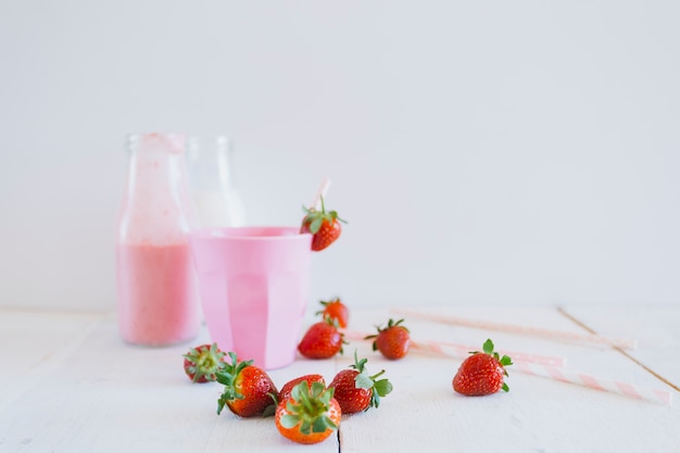 Strawberries near cup and milkshake
