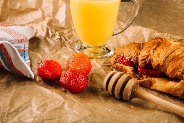 Strawberries near glass of juice and croissant