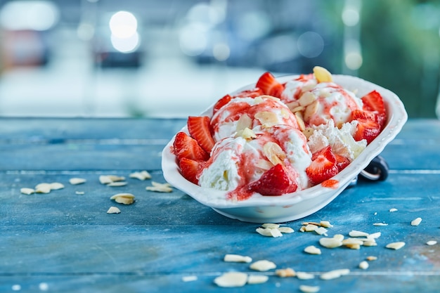 白いプレートに振りかけるストロベリーバニラアイスクリーム