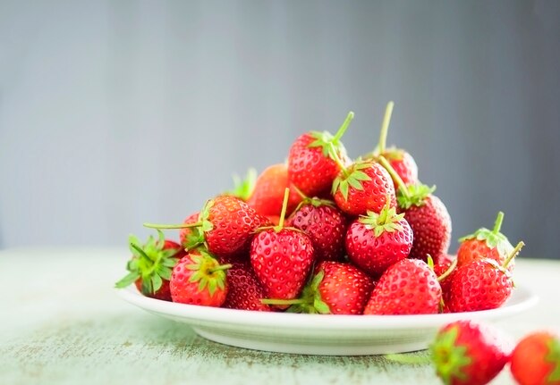 Strawberries in white plate over gray gradient background