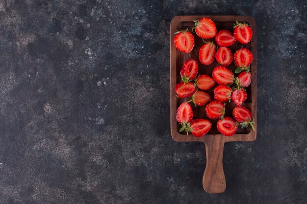 Strawberries on a wooden board on the grey marble, top view