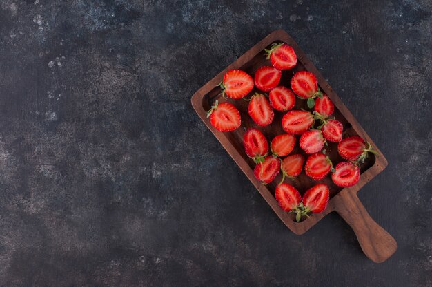 Strawberries on a wooden board on the grey marble