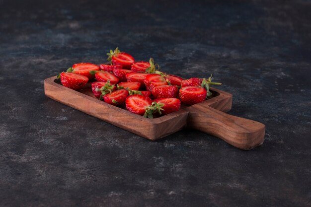 Strawberries on a wooden board on the grey marble