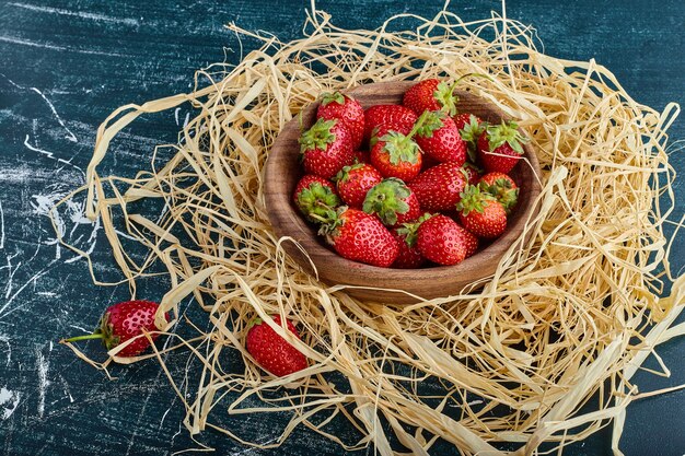 Strawberries in a wooden cup in the nest. 