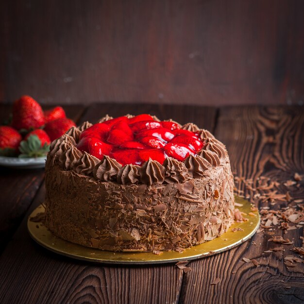 Strawberry, chocolate fruit cake and fresh strawberry on wooden table