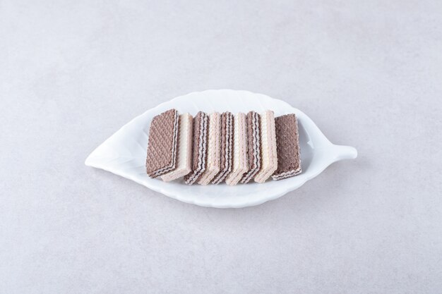 Strawberry and chocolate wafers on a plate on marble table.