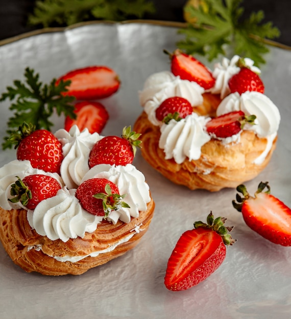 Strawberry choux pastry topped with white cream and strawberries