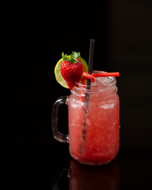 strawberry cocktail with shaved ice and garnished with lime and strawberry