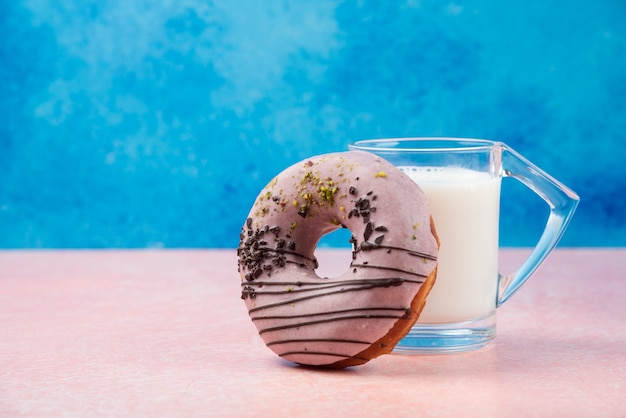 Free photo strawberry donut with decorations and a glass of milk on pink table.