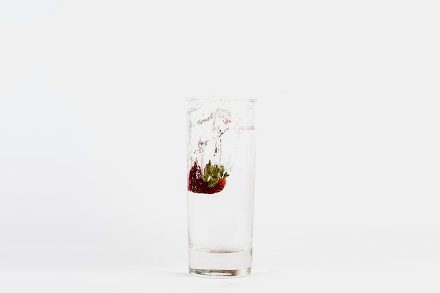 Free photo strawberry falling into glass of water