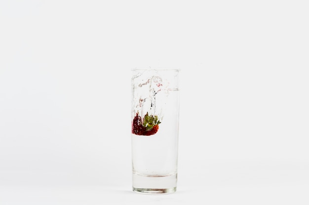 Strawberry falling into glass of water