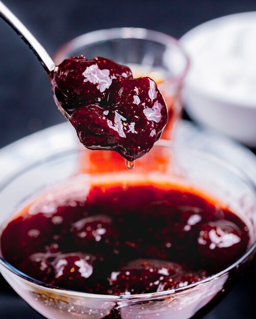 Strawberry jam pouring from the spoon in the glassware side view