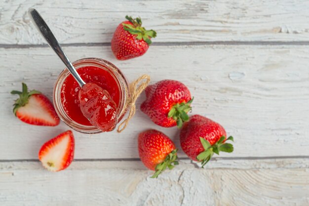 Strawberry jam on white rusric wooden background
