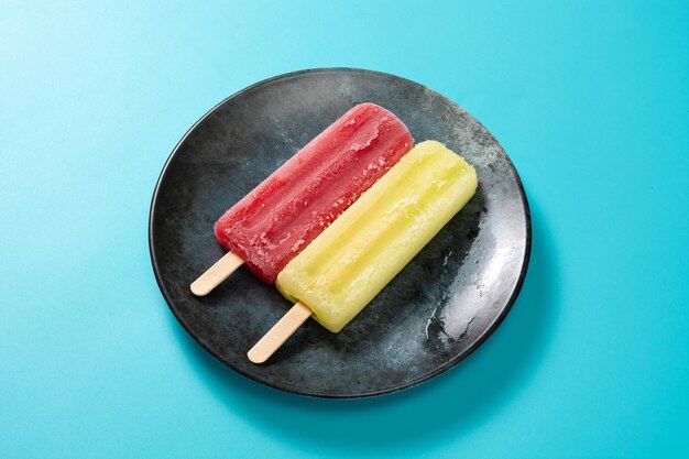 Strawberry and lemon popsicles on blue background