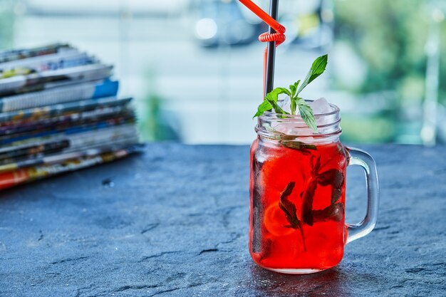 Limonata alla fragola con ghiaccio, menta paglia nella superficie scura