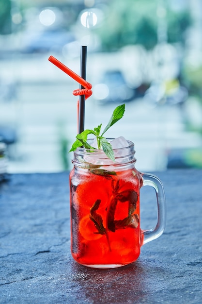 Strawberry lemonade with ice, straw mint in the dark surface 