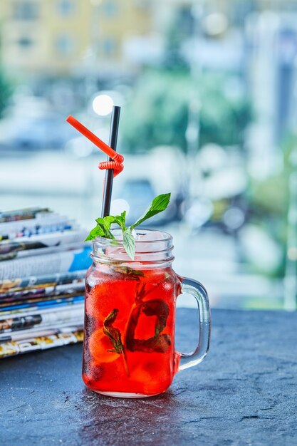 Strawberry lemonade with ice, straw mint in the dark surface 