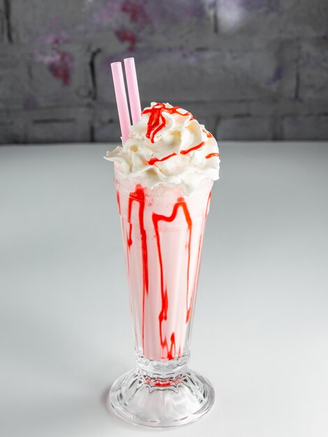 Strawberry milkshake with whipped cream and strawberry syrup