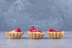 Free photo strawberry syrup-topped cupcakes lined-up on marble