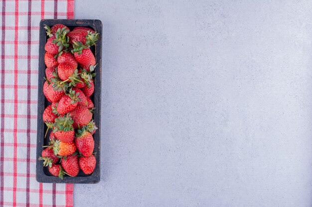 Strawberry tray lined up at the edge of the tablecloth on marble background. High quality photo