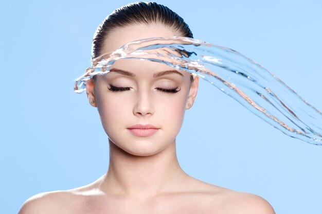 Stream of clean water before beautiful face of young teen - blue background