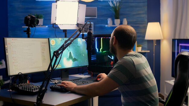 Streamer man sitting on gaming chair and start playing space shooter video game during online tournament