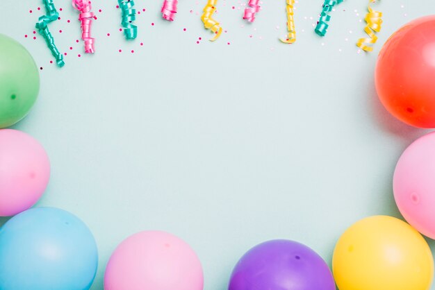 Streamers and colorful balloons on blue backdrop with space for text
