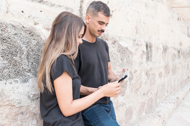 Streaming concept with couple leaning against wall