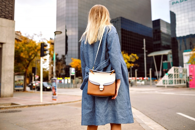 블루 코트와 세련된 가방을 입고 금발 여자의 스트리트 패션 초상화, 뉴욕 관광, 봄 가을 추운 계절 포즈.