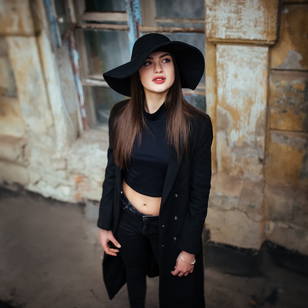 Street portrait of young casual lady in hat, black clothes, red lips