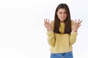 Бесплатное фото Стрессовая и злая яростная молодая женщина чувствует ярость и разочарование, пожимая руки агрессивной гримасой, злится, ругается из-за неудачи, стоя в ярости на белом фоне