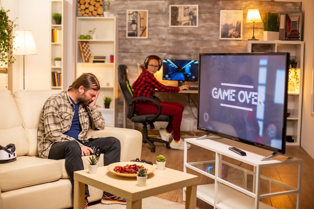 Stressed and angry male gamer losing a game while playing late at night in the living room