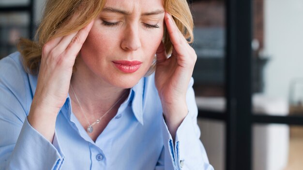 Stressed blond business woman holding head 