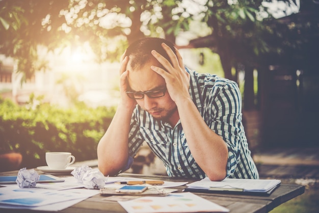 Free photo stressed businessman with papers and charts sitting at table at home. businessman with paperwork and deadline concept.