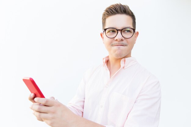 Stressed guy in eyeglasses holding smartphone