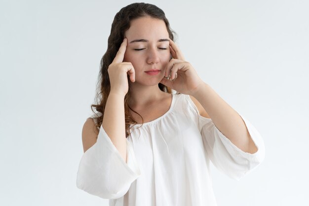 Stressed lovely woman touching temples and thinking hard