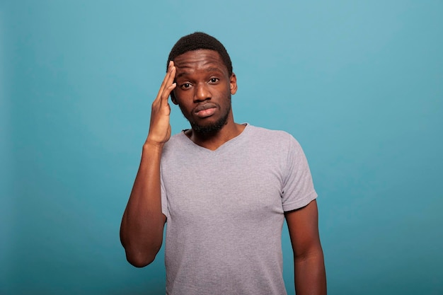 Stressed man dealing with headache and rubbing temples to stop pain, feeling unhappy and worried about health care problems. Frustrated person with migraine feeling tension and suffering.