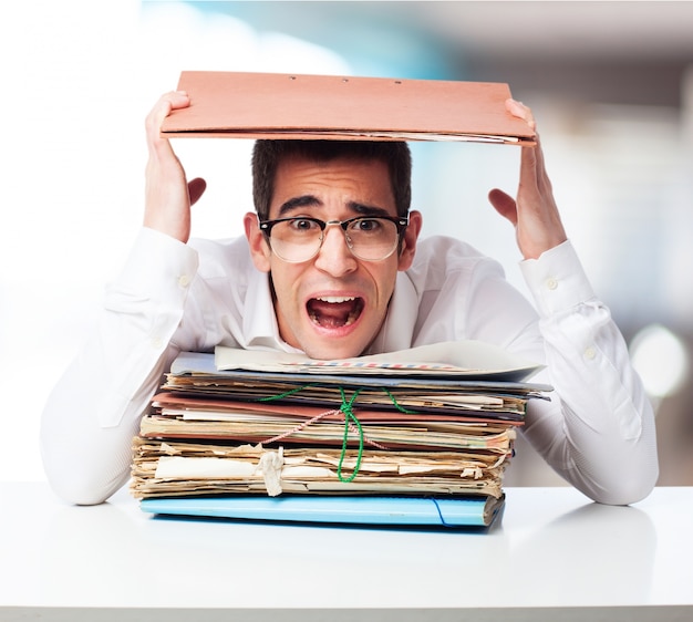 Free photo stressed man looking at a mountain of folders and screaming