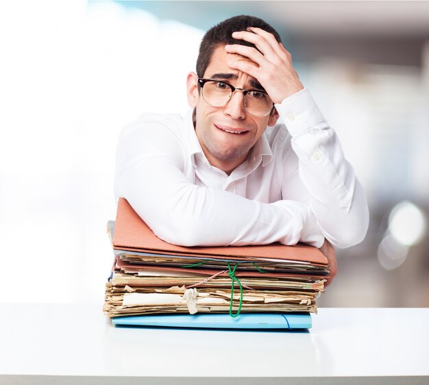 Stressed man looking at a mountain of folders